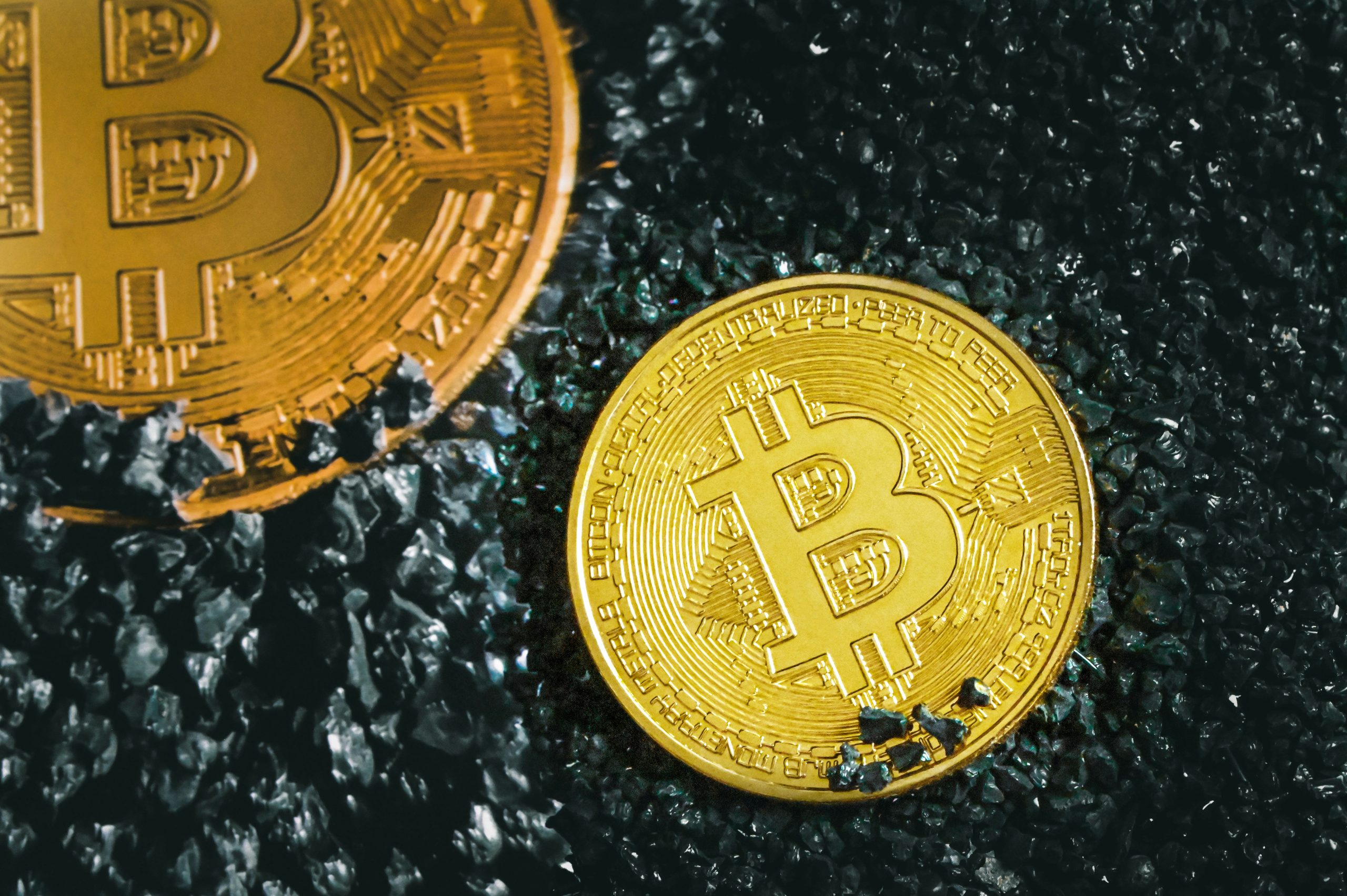 Two bitcoin coins on a charcoal grit background